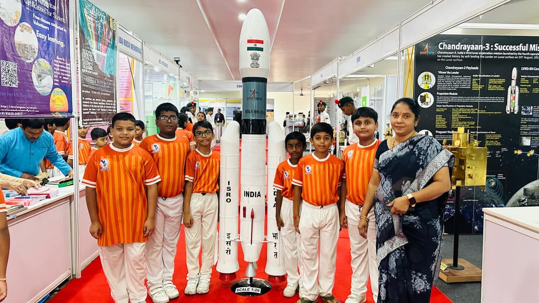 Students standing beside an ISRO launch vehicle model at Bharat Pride